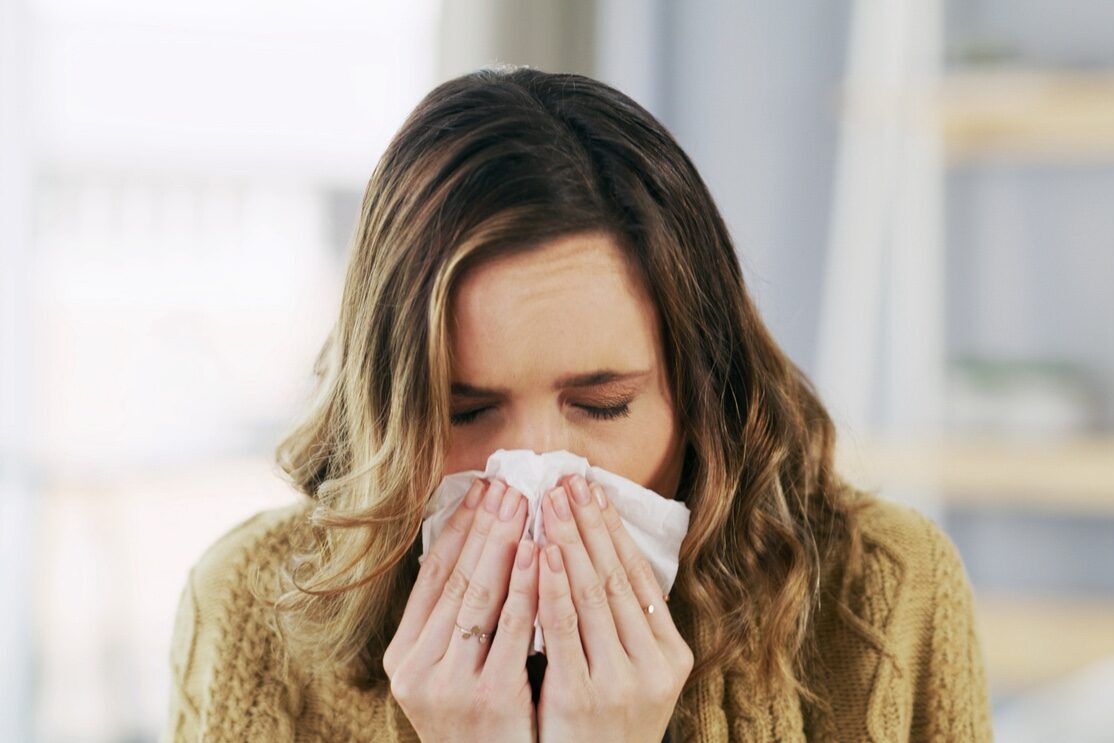 Frau schnäuzt in ihr Taschentuch